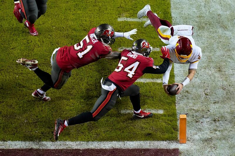 Washington Football Team quarterback Taylor Heinicke (4) dives towards the end zone to score a touchdown against Tampa Bay Buccaneers inside linebackers Kevin Minter (51) and Lavonte David (54) during the second half of an NFL wild-card playoff football game, in Landover, Maryland. AP Photo