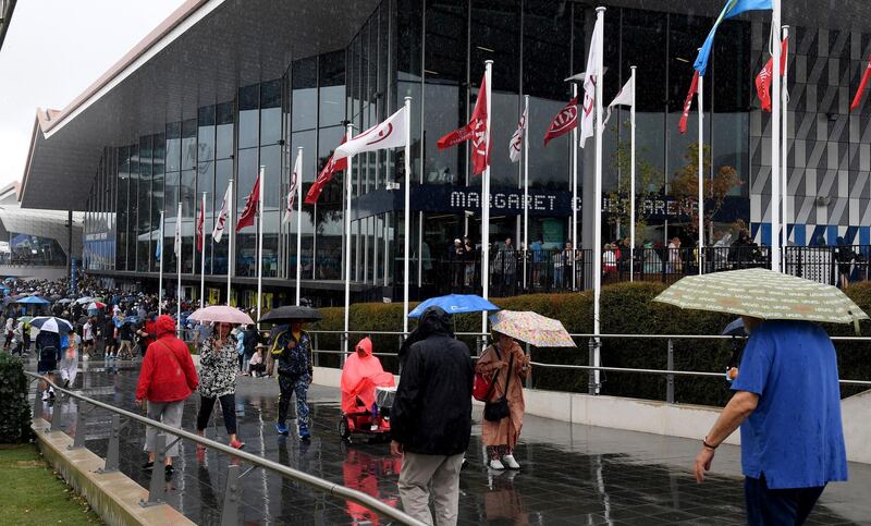 Spectators walk in wet weather gear as rain stops play on the outside courts during their first round singles match at the Australian Open tennis championship in Melbourne, Australia. AP Photo