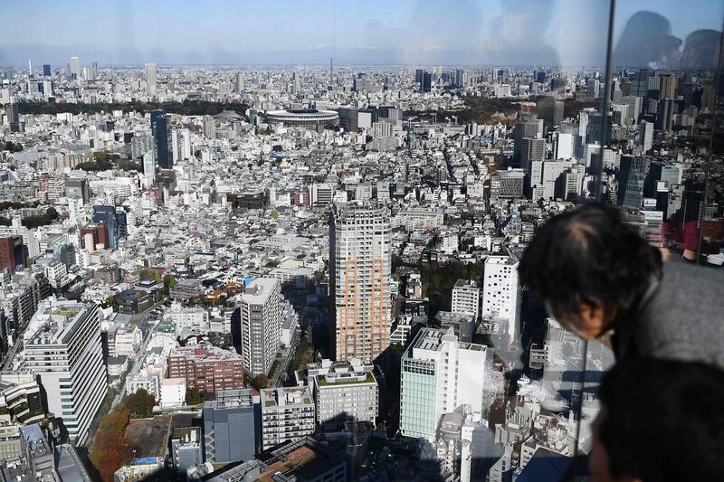 People look out a window at the completed Tokyo 2020 Olympic Games stadium. AFP