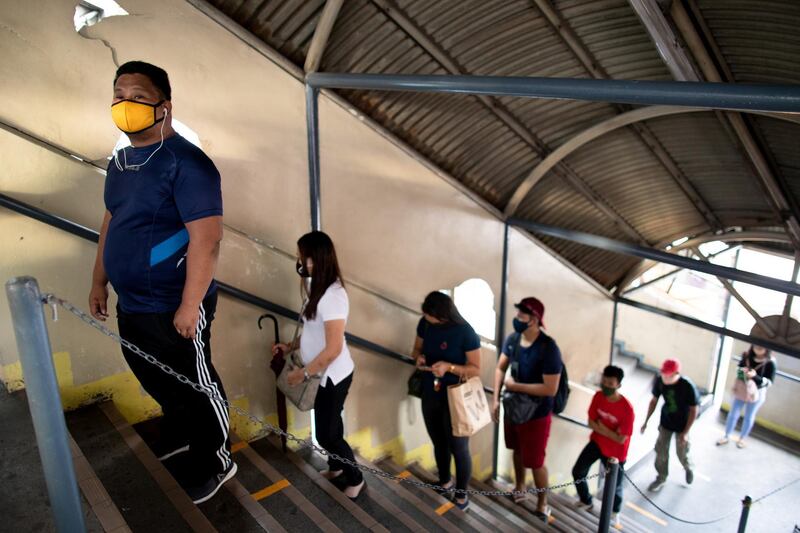 Passengers stand on social distancing markers as they queue to enter a train station on its first day of reopening since the lockdown.  Reuters