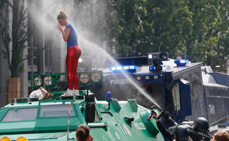 A demonstrator standing on a police vehicle is sprayed by a water cannon before the opening day of the G20 summit in Hamburg, Germany,.  Ronny Wittek / EPA