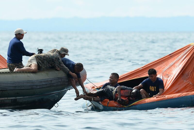 Philippine Navy personnel lift a victim from one of the floating life rafts during rescue operations on August 17, 2013 after a cargo ship collided with the ferry St. Thomas Aquinas the night before off the town of Talisay near the Philippines' second largest city of Cebu. Philippine rescuers searched on August 17 for more than 200 people missing after the ferry collided with the cargo ship in thick darkness and sank almost instantly, with 26 already confirmed dead.     AFP PHOTO / TED ALJIBE
 *** Local Caption ***  754946-01-08.jpg