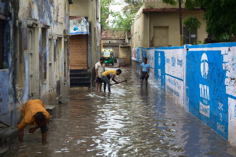 Men work to drain a waterlogged lane following heavy rains in Mandvi. AFP