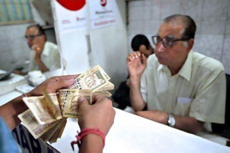 Counting Indian rupees at a money exchange in New Delhi. The rupee touched a record low of 59.93 to the dollar on Thursday. Saurabh Das / AP Photo