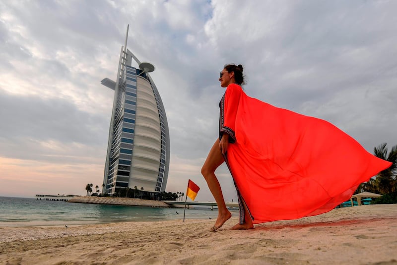 A woman bather walks along the beach shoreline near the Burj Al Arab hotel in Dubai.   AFP