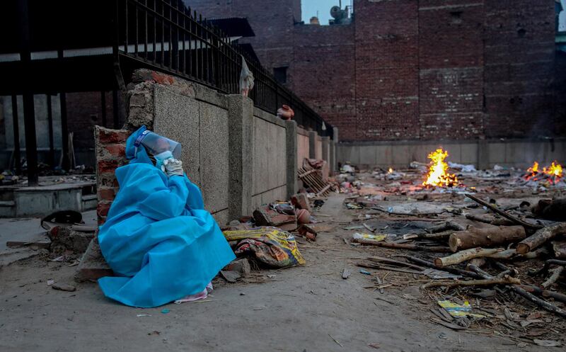 epa09186383 A relative wearing Personal Protective Equipment (PPE) mourns during the last rites of a covid-19 victim at a makeshift cremation ground in New Delhi, India, 08 May 2021. According to the Indian Ministry of Health, India recorded 404,000 fresh Covid-19 cases in the 24 hours leading to 08 May.  EPA/RAJAT GUPTA