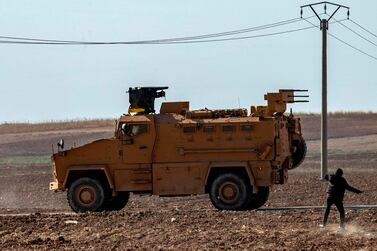 A Syrian youth throws a stone towards Turkish military vehicles during a joint patrol on Monday. AFP