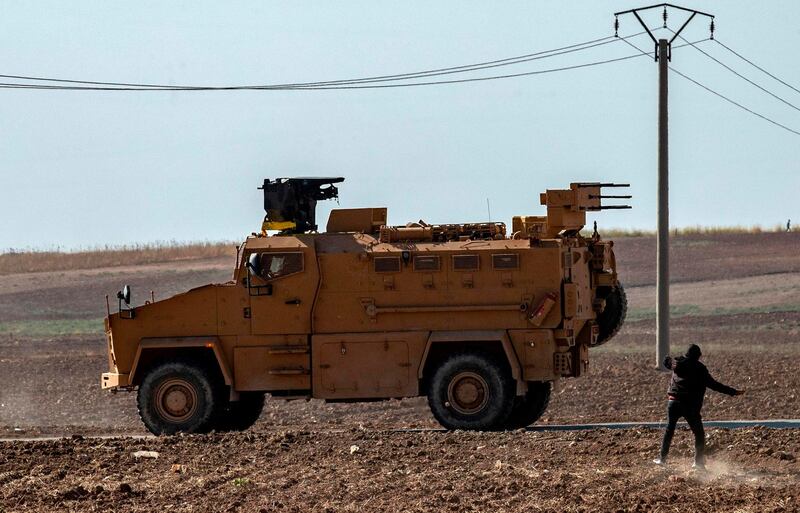 A Syrian youth throws a stone towards Turkish military vehicles during a Turkish-Russian army patrol near the town of Darbasiyah in Syria's northeastern Hasakeh province along the Syria-Turkey border on November 11, 2019. / AFP / Delil SOULEIMAN
