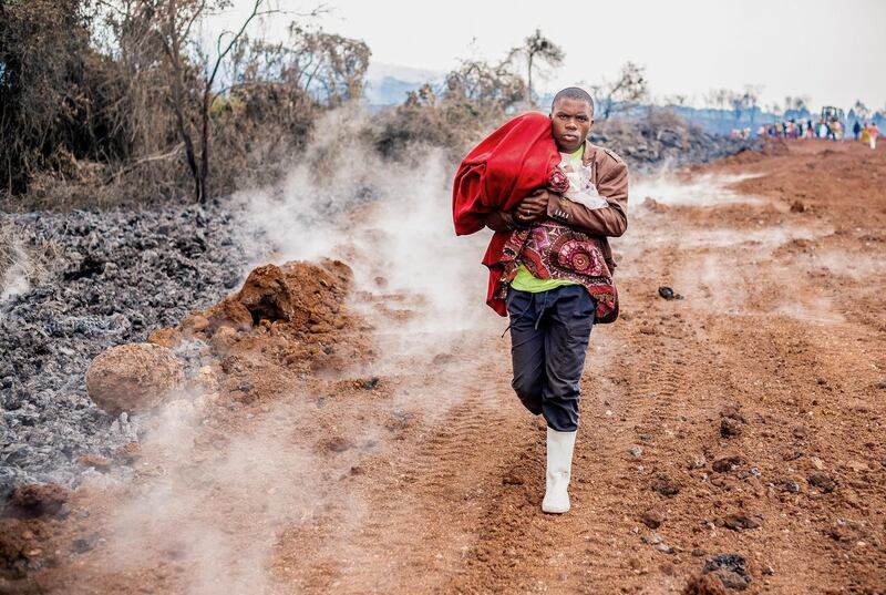 A man carrying a child flees the city of Goma, in the Democratic Republic of the Congo, following warnings that Mount Nyiragongo, 10 kilometres away, may erupt for a second time in just over a week. EPA