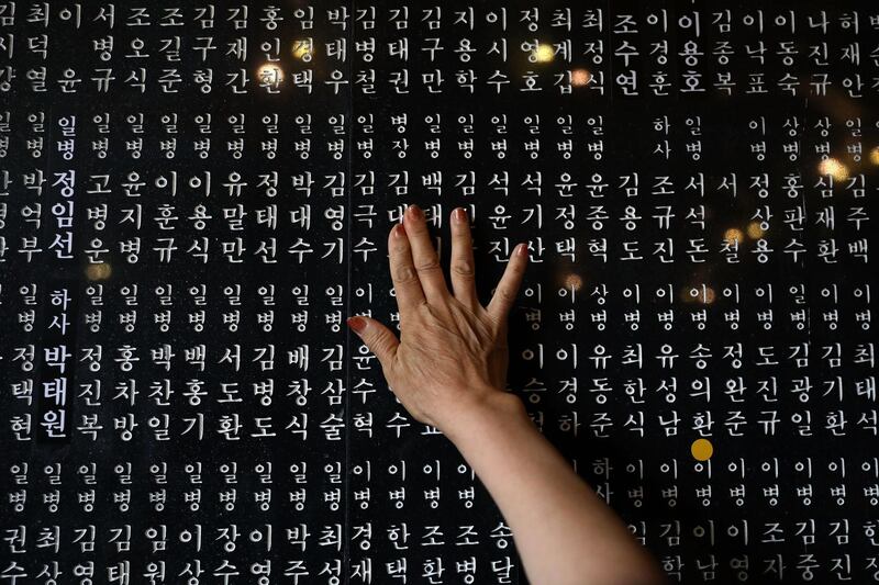 A South Korean woman touches the engraved name of her older brother who died during the Korean War at Seoul National Cemetery. Chung Sung-Jun / Getty Images