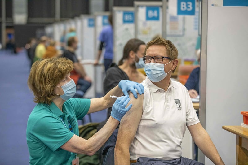 People receive a dose of a Covid-19 vaccine at a temporary clinic set up in the Titanic Exhibition Centre in Belfast. AFP
