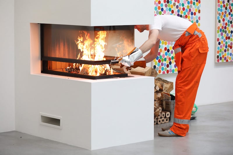 An assistant burns an art piece by British artist Damien Hirst during a photocall at the Newport Street Gallery. AFP