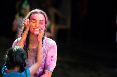 A visually impaired Indian student from The Devnar School for the Blind apply coloured powder to a teacher as they celebrate the Holi festival in Hyderabad on March 21, 2019.  Holi, the popular Hindu spring festival of colours is observed in India at the end of the winter season on the last full moon of the lunar month. / AFP / NOAH SEELAM
