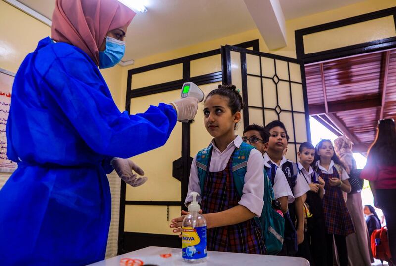 A staff member of the Rosary Sisters school in Gaza City checks the temperature of returning students on the first day of school. AFP