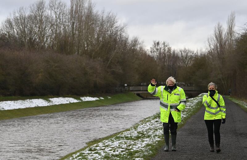 British Prime Minister Boris Johnson walks with Environment Agency workers during a visit to a storm basin near the River Mersey in Didsbury. AFP