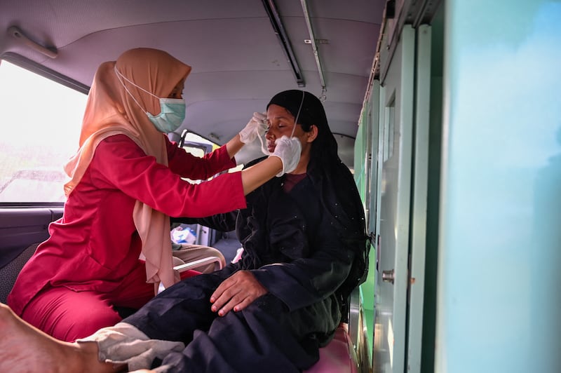 A health worker helps a Rohingya refugee after she arrived by boat on the coast of Aceh. AFP