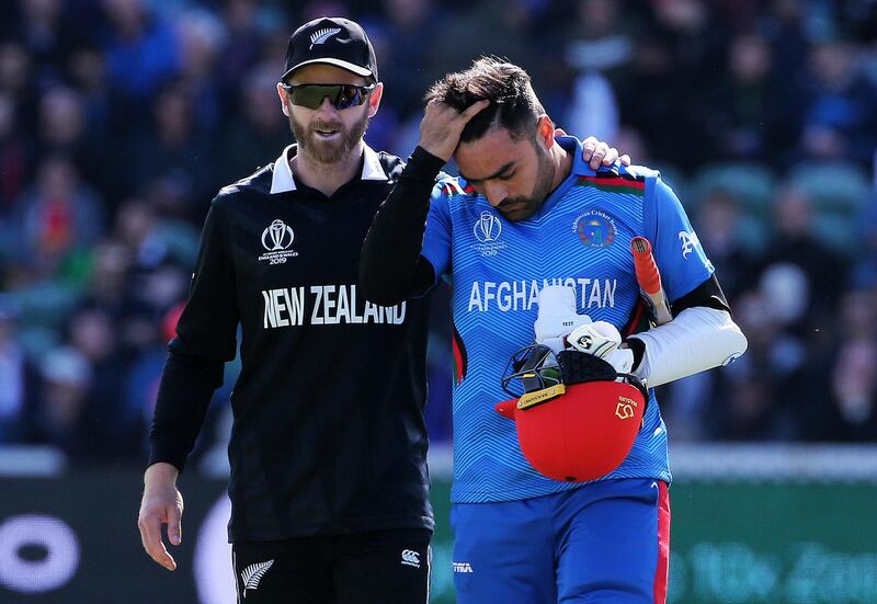 New Zealand's Kane Williamson, left checks on Afghanistan's Rashid Khan after a ball bowled by Lockie Ferguson bounced off Rashid's helmet and onto the stump during the ICC Cricket World Cup group stage match between Afghanistan and New Zeland, at the County Ground Taunton, England, Saturday, June 8, 2019. (Mark Kerton/PA via AP)