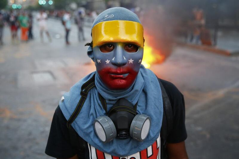 An anti-government protester, wearing a mask in the colours of the Venezuelan flag, stands at a barricade during riots in Caracas. Jorge Silva/ Reuters 