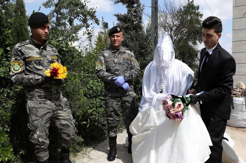 Palestinian Groom Malik Abu Ghazaleh and his bride Afnan Salah receive flowers from a Palestinian security officer during their wedding without any guests, in the West Bank city of Hebron, on April 2, 2020. Palestinian Authority restrictions forbid gatherings to prevent the spread of the coronavirus. EPA
