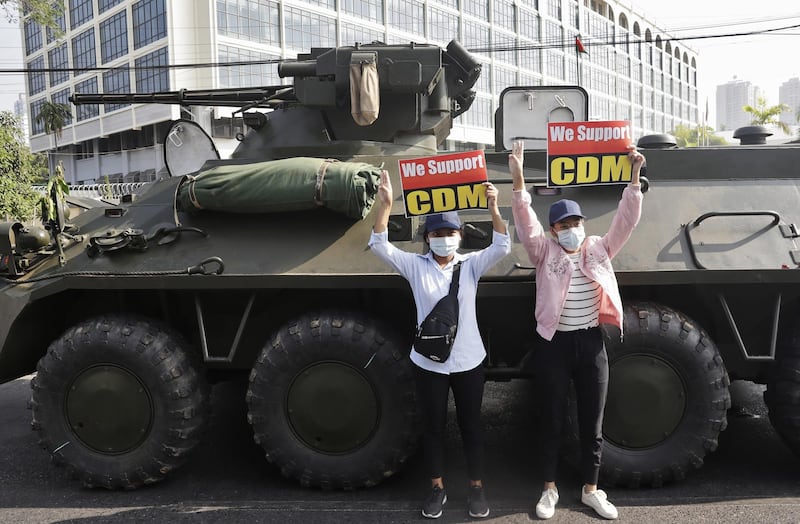 Demonstrators hold up placards in front of an armoured vehicle during a protest outside the Central Bank in Yangon, Myanmar. EPA