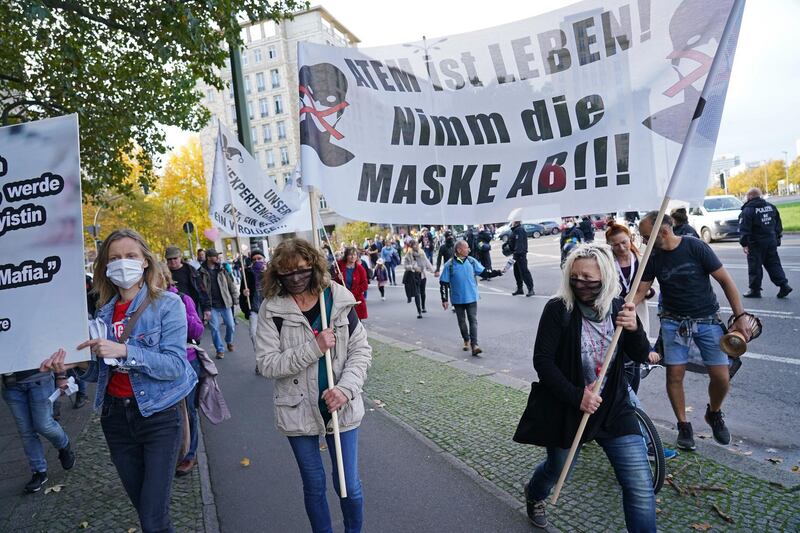 BERLIN, GERMANY - OCTOBER 25: Protesters, including two women holding a banner that reads: "Breath is life! Take off the mask!", march to the Kosmos events venue where the World Health Summit was originally scheduled to take place on October 25, 2020 in Berlin, Germany. Several thousand protesters, including coronavirus skeptics, anti-vaccine activists, supporters of the Querdenken movement and coronavirus restrictions opponents, marched to the venue to voice their opposition to the German government's restrictions on public life. The World Health Summit was originally scheduled with in-person events but was relegated to online only as a precaution against infection. Germany has seen a dramatic upswing in coronavirus infections over recent weeks with new daily records of confirmed cases.  (Photo by Sean Gallup/Getty Images)