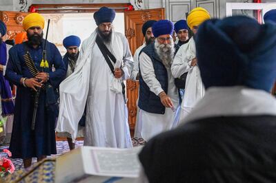 'Waris Punjab De' chief Amritpal Singh, centre, pays his respects to Guru Granth Sahib, the Sikh holy book, at the Golden Temple in Amritsar on March 3.  (AFP)