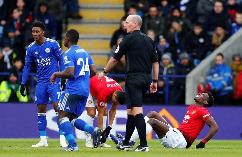 Pogba reacts after sustaining an injury while Leicester City's Demarai Gray looks on. Reuters