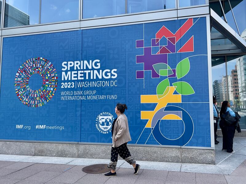 A woman walks past a sign for the 2023 Spring Meetings of the World Bank and International Monetary Fund in Washington, DC. The meetings will take place in person from April 10 to April 16. AFP