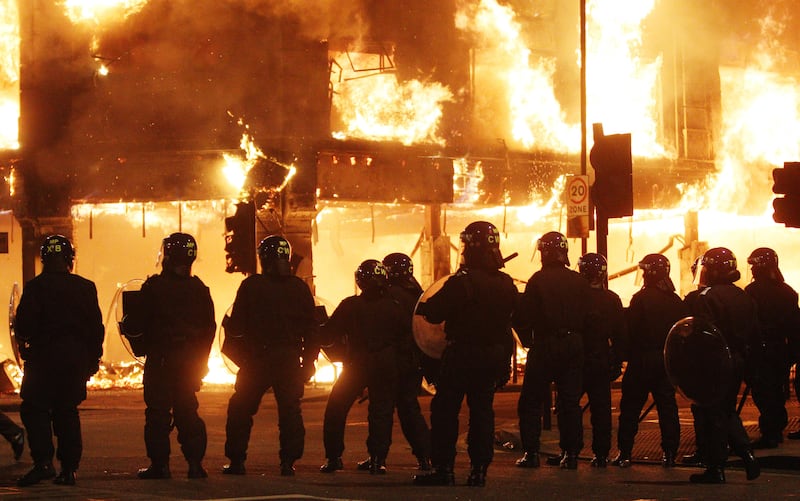 Riot police stand in line as fire rages through a building in Tottenham, north London.