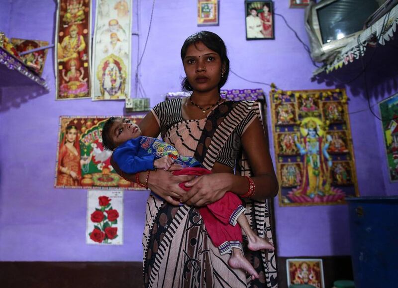 Five-year-old Saagar, who suffers from mental and physical disabilities is held by his mother Komal, as she poses for a picture at their house in a slum in Bhopal.