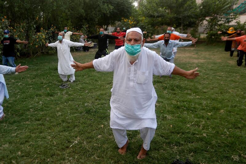 An elderly person wearing a mask to help curb the spread of the coronavirus attends a Yoga class at a park in Lahore, Pakistan.  AP