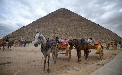 This picture taken on December 29, 2018 shows tourist horse-drawn carts waiting by the base of the Great Pyramid of Khufu (or Cheops) at the Giza necropolis on the southwestern outskirts of the Egyptian capital Cairo on December 29, 2018.  / AFP / MOHAMED EL-SHAHED                   
