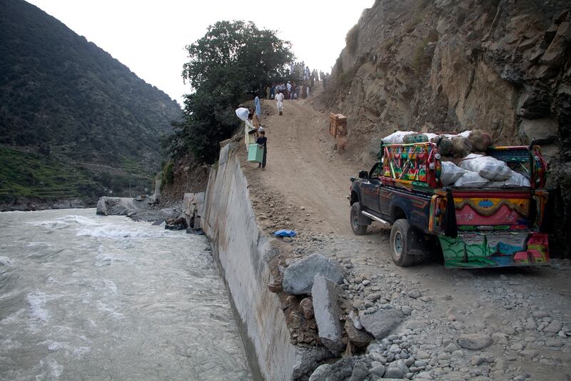 Displaced people wait by a damaged road next to floodwaters in Kalam Valley, in northern Pakistan. AP
