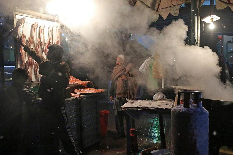An Afghan man, center, waits as he buys fish at a street stall street during a snow storm in Kabul, Afghanistan. Massoud Hossaini / AP Photo