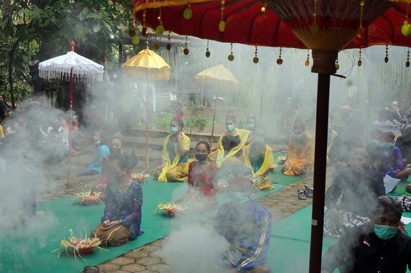 People wearing protective face masks take part in rituals amid a surge of coronavirus disease (COVID-19) cases in Tulungagung, East Java province, Indonesia.