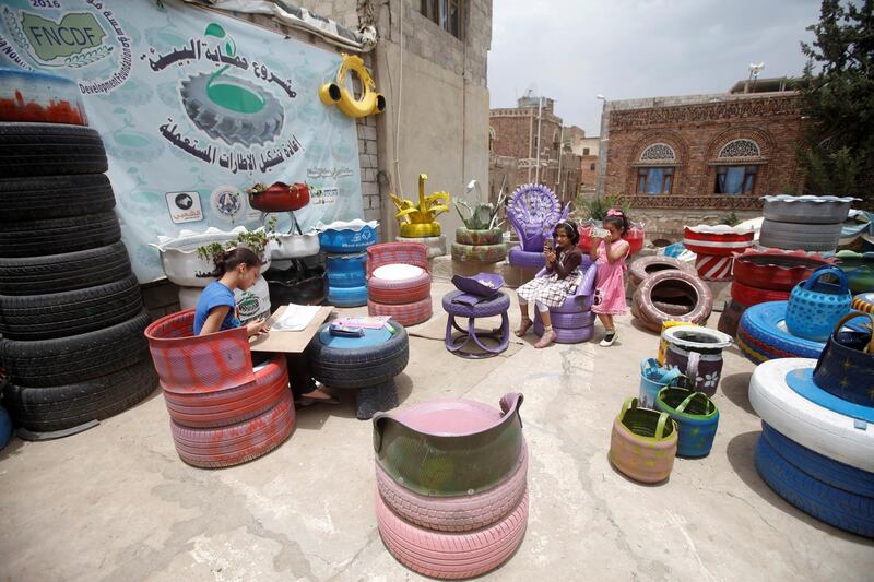 Daughters of Sufian Noaman sit at his tire recycling workshop in Sanaa, Yemen.  Reuters