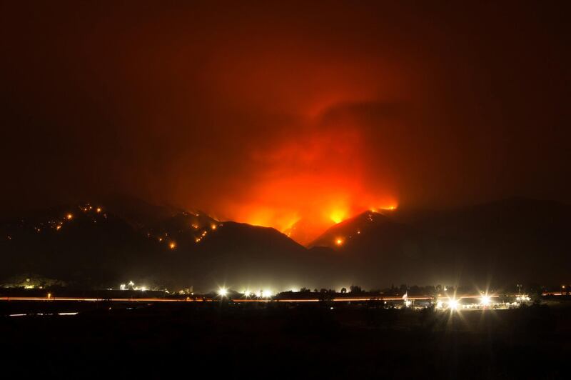 The Holy Fire burns in the distance above I-15 on Thursday night, Aug. 9, 2018 in Temescal Valley, Calif.  More than a thousand firefighters battled to keep a raging Southern California forest fire from reaching foothill neighborhoods Friday before the expected return of blustery winds that drove the flames to new ferocity a day earlier. (AP Photo/Patrick Record)