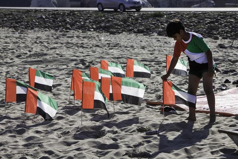 A young boy admires a series of flags laid out by his family as they camped on a beach near Dibba. Matching the theme of their camp, most members of the family were wearing celebratory scarves. Jaime Puebla / The National