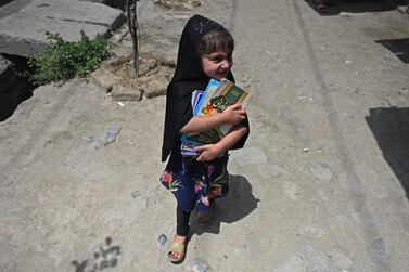 A girl carrying books walks along a street in the old quarters of Kabul on July 12, 2021.  (Photo by Sajjad HUSSAIN  /  AFP)