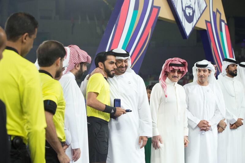 AL AIN, UNITED ARAB EMIRATES - April 18, 2019: HH Sheikh Mohamed bin Zayed Al Nahyan Crown Prince of Abu Dhabi Deputy Supreme Commander of the UAE Armed Forces (4th R) stands for a photograph with a referee after Etoile du Sahel won the 2018–19 Zayed Champions Cup, at Hazza bin Zayed Stadium. Seen with HH Sheikh Nasser bin Hamad bin Isa Al Khalifa, Representative of His Majesty the King for Charity Works and Youth Affairs and Chairman of the Board of Trustees of the Royal Charity Organisation of Bahrain (R), HH Sheikh Hazza bin Zayed Al Nahyan, Vice Chairman of the Abu Dhabi Executive Council (2nd R), HRH Prince Alwaleed bin Talal bin Abdulaziz Al Saud (3rd R) and HE Turki bin Abdul Mohsen Al Sheikh, Chairman of the General Entertainment Authority of Saudi Arabia (6th R).

( Mohammed Al Bloushi for Ministry of Presidential Affairs )
---