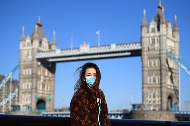 A woman poses for a photo next to London's Tower Bridge in a year when wearing a protective mask became the norm. Getty