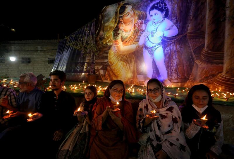 A Hindu family hold clay lamps during a ceremony to celebrate Diwali, the festival of lights, at Swami Narayan temple in Karachi, Pakistan. AP Photo