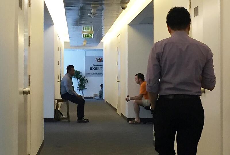 Investors and staff sit outside the closed office of Exential in Dubai Media City. Pawan Singh / The National