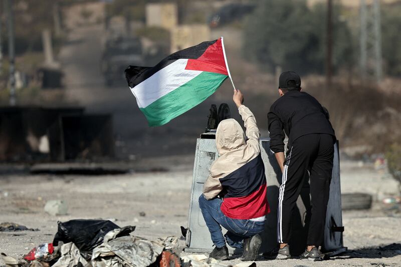 Palestinian boys wave their national flag as demonstrators clash with Israeli soldiers during a protest in Ramallah in the occupied West Bank. AFP