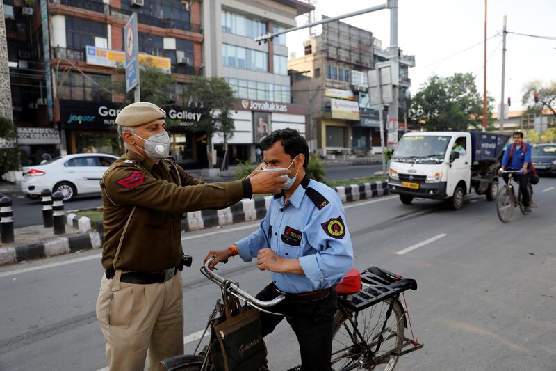 A policeman adjusts the mask of a security guard in New Delhi, India. Reuters