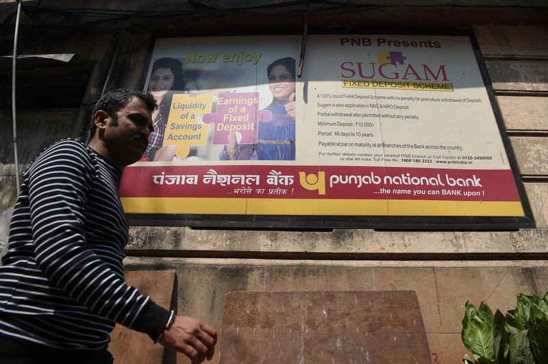 An Indian man walks past a sign for the state-owned Punjab National Bank (PNB) in Mumbai on February 14, 2018.
India's second-largest state-run bank said February 14 it had detected fraud of almost $1.8 billion at one of its branches, sending its shares plunging more than seven percent. The PNB, one of several state-owned lenders the government is trying to clean up, said transactions worth $1.77 billion had been made "for the benefit of a few select account holders with their apparent connivance". / AFP PHOTO / INDRANIL MUKHERJEE