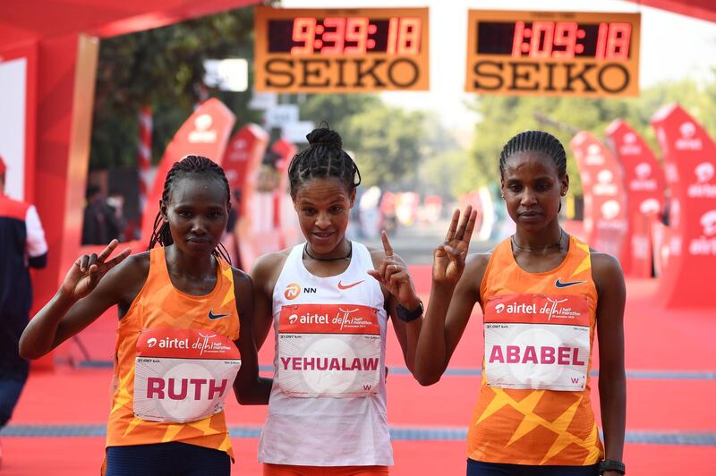 First placed Ethiopian Yalemzerf Yehualaw, centre, with second placed Kenyan Ruth Chepngetich and third placed Ethiopian Ababel Yeshaneh at the finish line of the Delhi Half Marathon. AFP