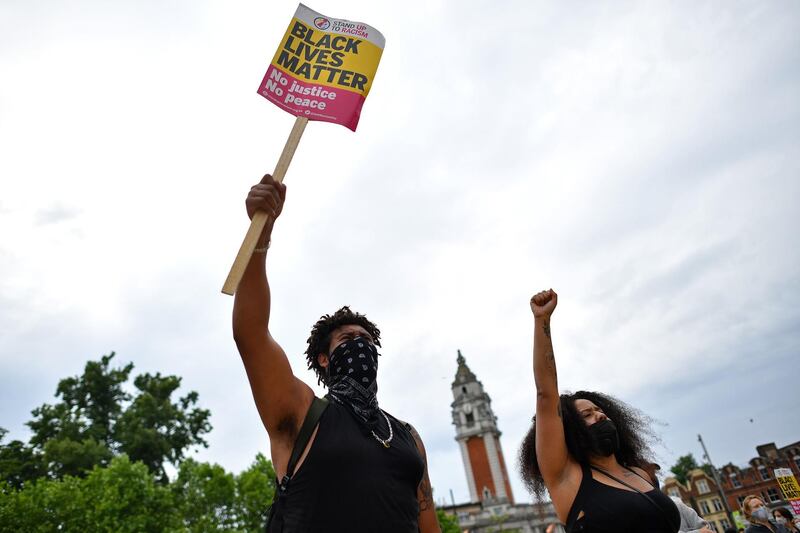 People hold placards as they gather for an anti-racism demonstration in Windrush Square, Brixton in south London. AFP