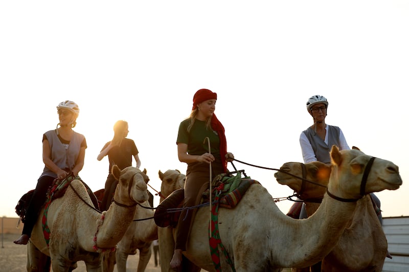 Ms Higgins (second from left) and Linda Krockenberger (third from left) at the Arabian Desert Camel Riding Centre in Dubai. Chris Whiteoak / The National