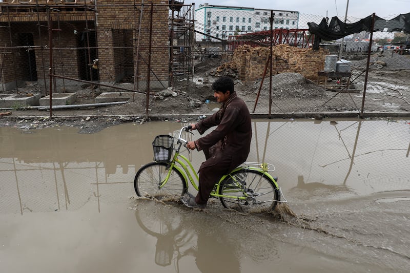 An Afghan man rides his bicycle on a flooded street